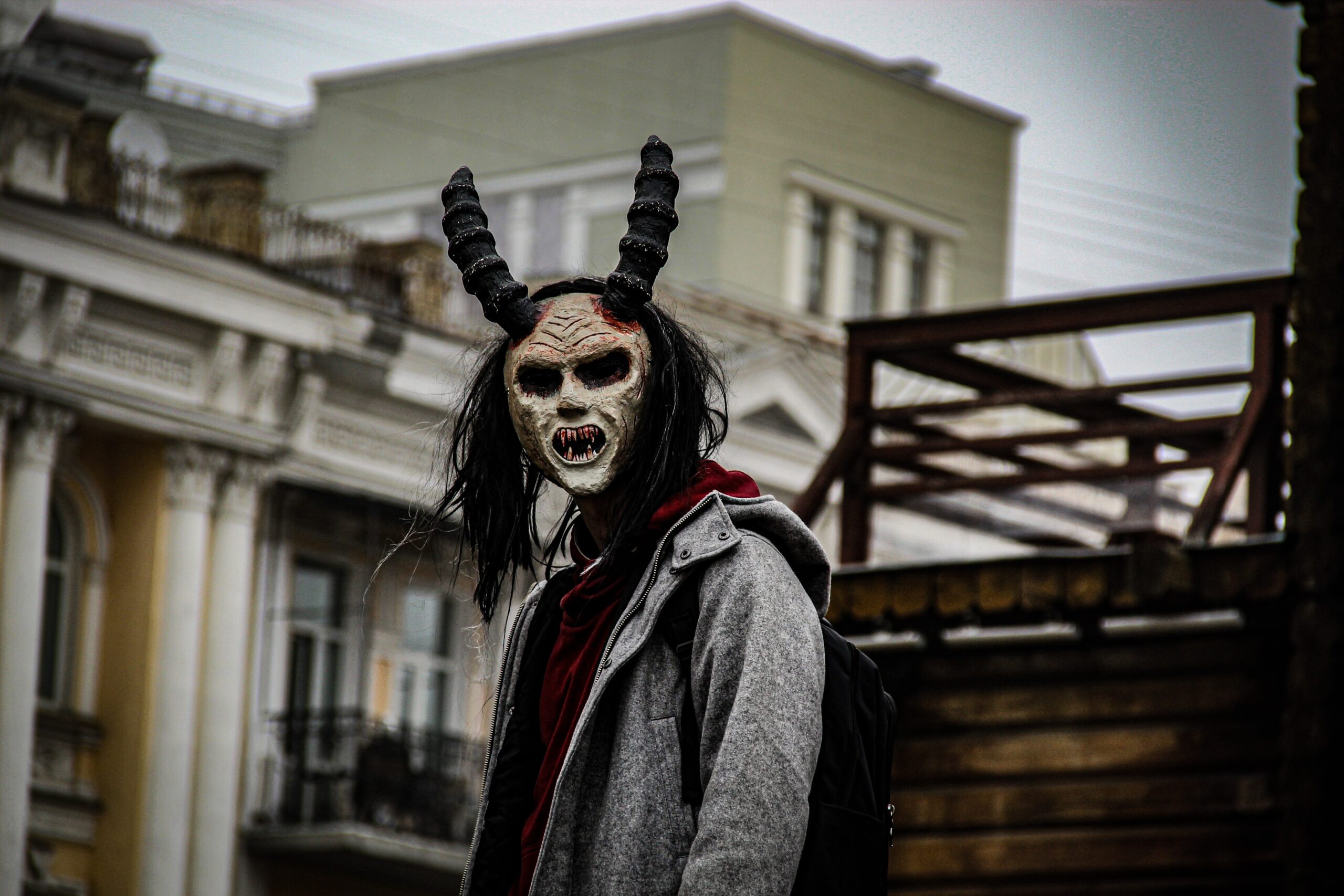 Long haired person in devil mask, amidst suburban setting in Ukraine.